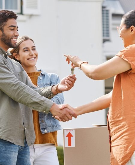 Keys, realtor handshake and couple moving to new house, property investment and mortgage success, deal or thank you. Young people shaking hands and giving lock to dream home and real estate agreement.